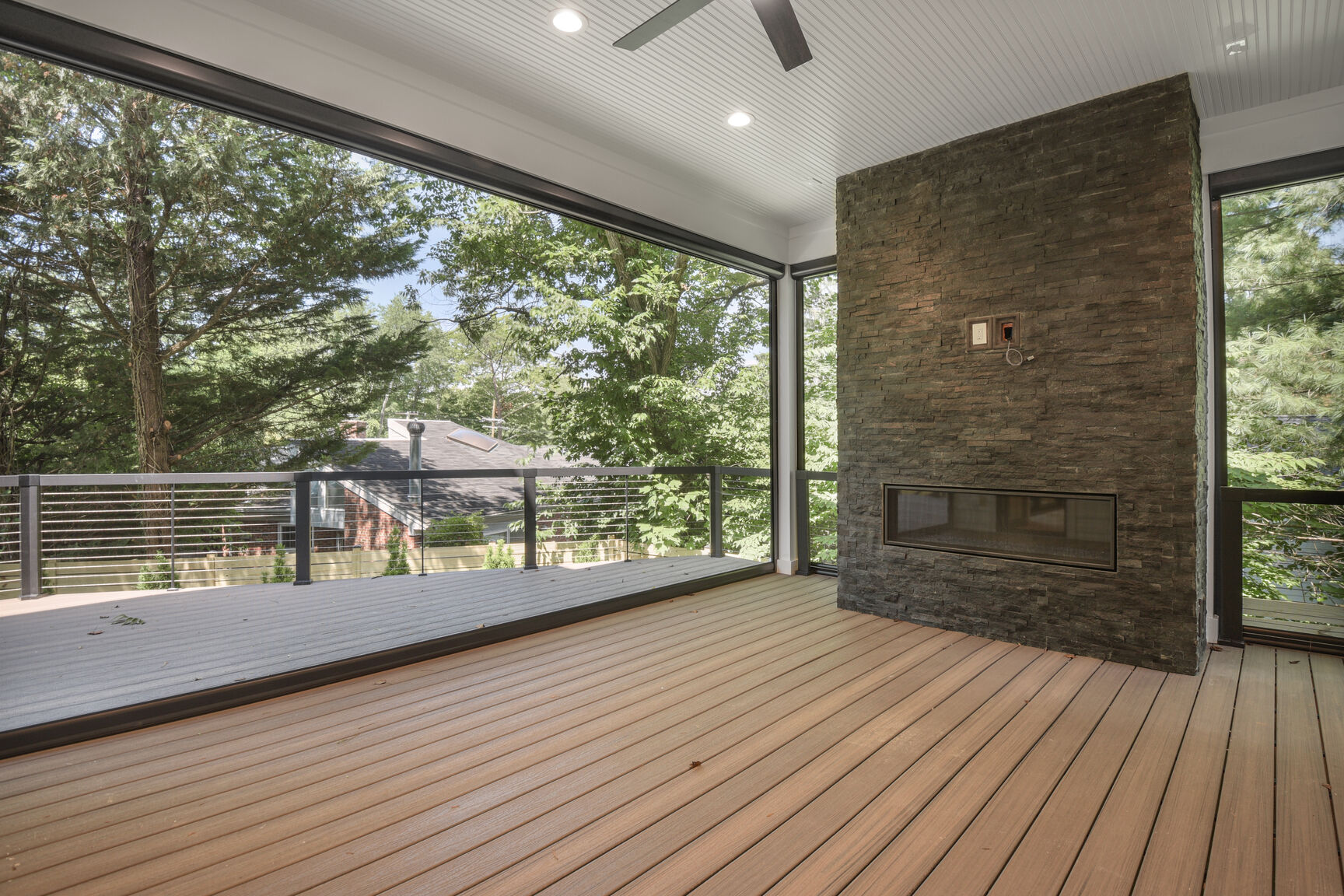Screened porch with stone fireplace and cable railing